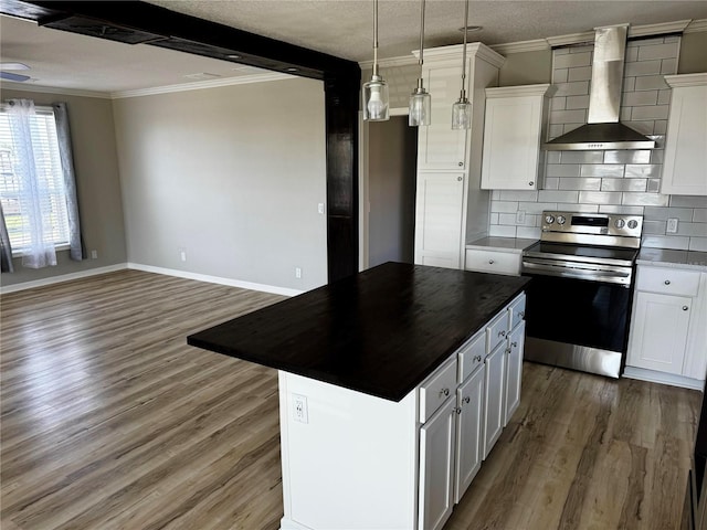 227 Bay St, Port St Joe, FL 32456 - kitchen featuring stainless steel range with electric cooktop, wall chimney range hood, wood finished floors, ornamental molding, and a textured ceiling
