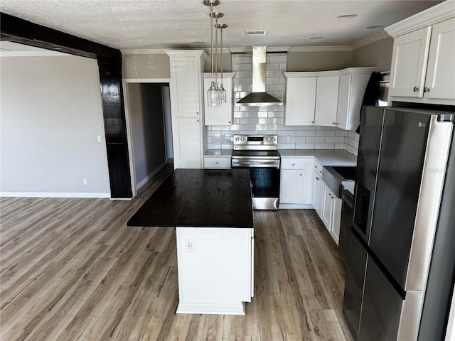 227 Bay St, Port St Joe, FL 32456 - kitchen featuring appliances with stainless steel finishes, wall chimney range hood, a kitchen island, decorative backsplash, and baseboards