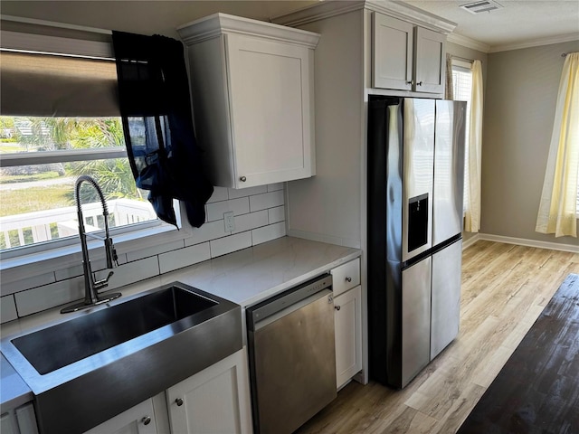 227 Bay St, Port St Joe, FL 32456 - kitchen featuring stainless steel appliances, backsplash, a sink, crown molding, and light wood finished floors