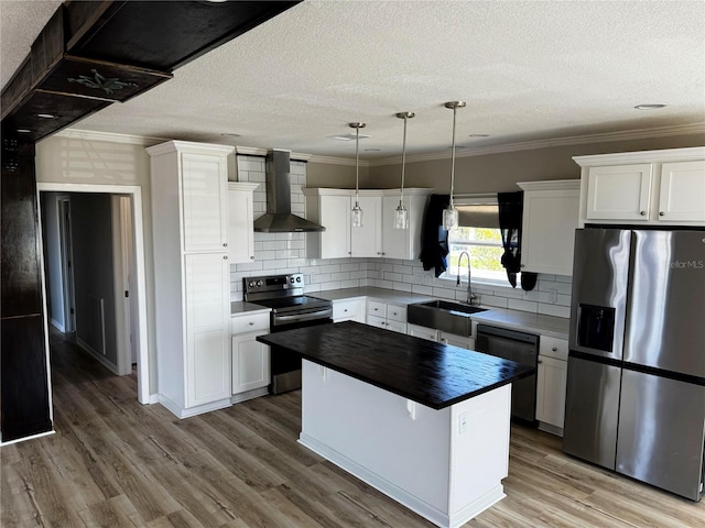227 Bay St, Port St Joe, FL 32456 - kitchen with appliances with stainless steel finishes, wall chimney exhaust hood, a sink, crown molding, and a kitchen island