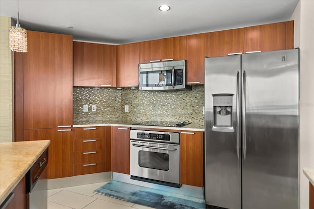 241 Riverside Dr Unit 902, Holly Hill, FL 32117 - kitchen with appliances with stainless steel finishes, brown cabinetry, tasteful backsplash, light tile patterned floors, and pendant lighting