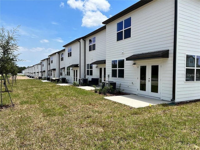 477 Madison Dr, Davenport, FL 33837 - rear view of house featuring french doors, a lawn, cooling unit, and a patio
