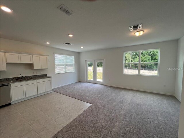 477 Madison Dr, Davenport, FL 33837 - kitchen featuring stainless steel dishwasher, light colored carpet, a sink, white cabinetry, and baseboards