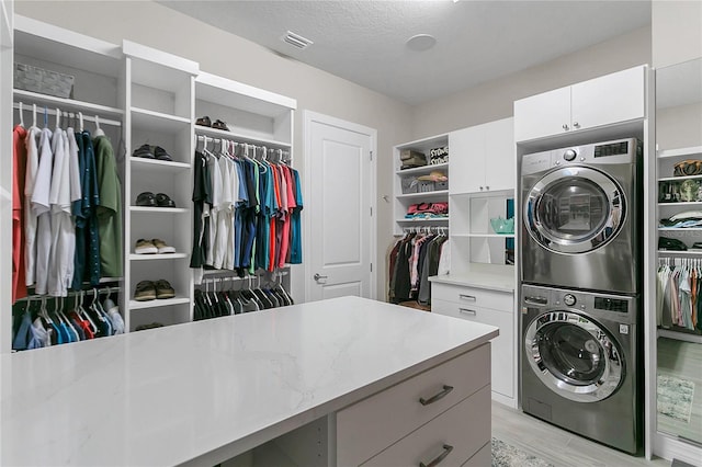 1938 Filly Trl, Oviedo, FL 32765 - washroom featuring stacked washer / drying machine, cabinet space, and light wood-style flooring
