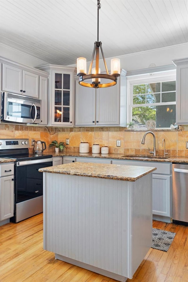 6501 Matchett Rd, Belle Isle, FL 32809 - kitchen with appliances with stainless steel finishes, a chandelier, backsplash, ornamental molding, and glass insert cabinets