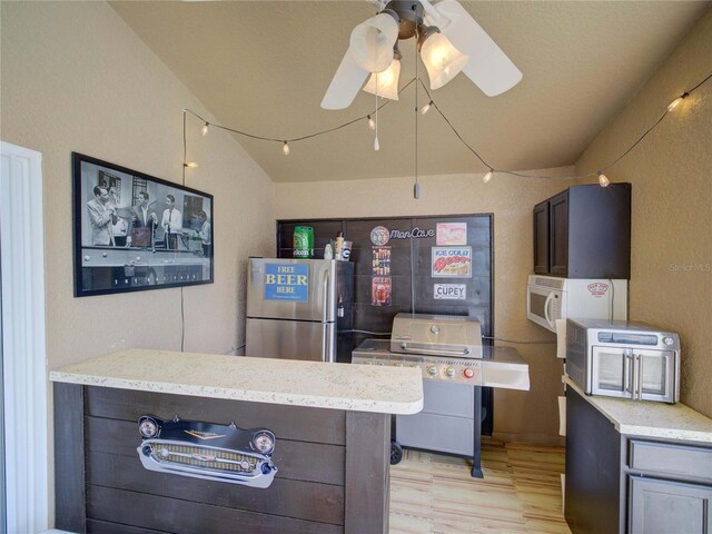 456 Old Bridge Cir, Davenport, FL 33897 - kitchen with freestanding refrigerator, light wood-type flooring, vaulted ceiling, white microwave, and light stone counters
