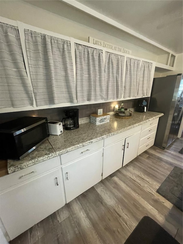 578 3rd St, Daytona Beach, FL 32117 - kitchen with stainless steel microwave, dark wood finished floors, white cabinetry, and light stone countertops