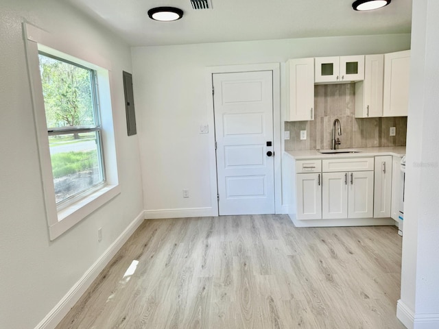38706 8th Ave, Zephyrhills, FL 33542 - kitchen featuring a sink, light wood finished floors, light countertops, white cabinetry, and backsplash