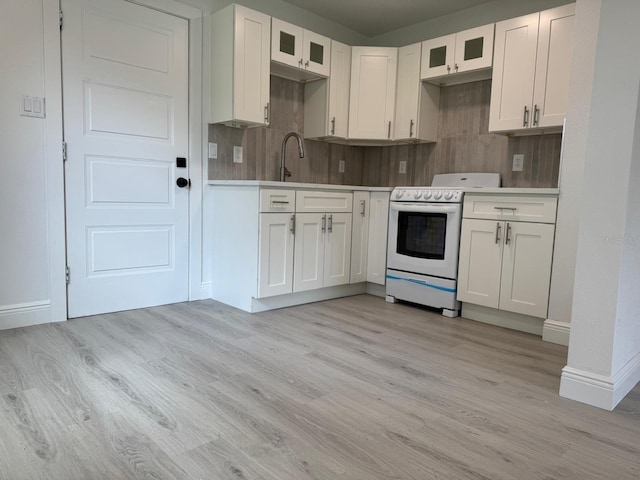 38706 8th Ave, Zephyrhills, FL 33542 - kitchen featuring white range with electric stovetop, light wood-style floors, backsplash, and white cabinetry