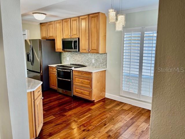 204 Quayside Cir Unit 601, Maitland, FL 32751 - kitchen featuring stainless steel appliances, light countertops, ornamental molding, backsplash, and dark wood finished floors
