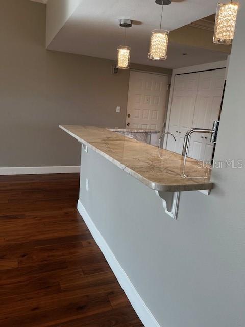 204 Quayside Cir Unit 601, Maitland, FL 32751 - kitchen with a breakfast bar area, dark wood-style floors, pendant lighting, and light stone counters