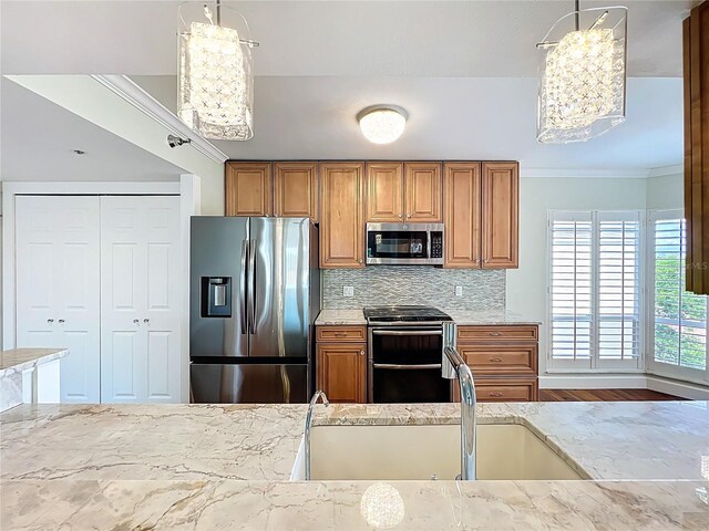 204 Quayside Cir Unit 601, Maitland, FL 32751 - kitchen featuring stainless steel appliances, a chandelier, brown cabinets, light stone countertops, and crown molding