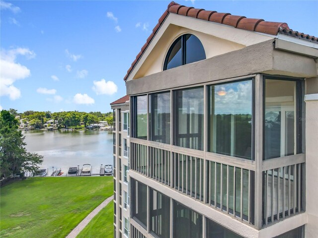 204 Quayside Cir Unit 601, Maitland, FL 32751 - view of home's exterior with a water view, stucco siding, a tiled roof, and a lawn