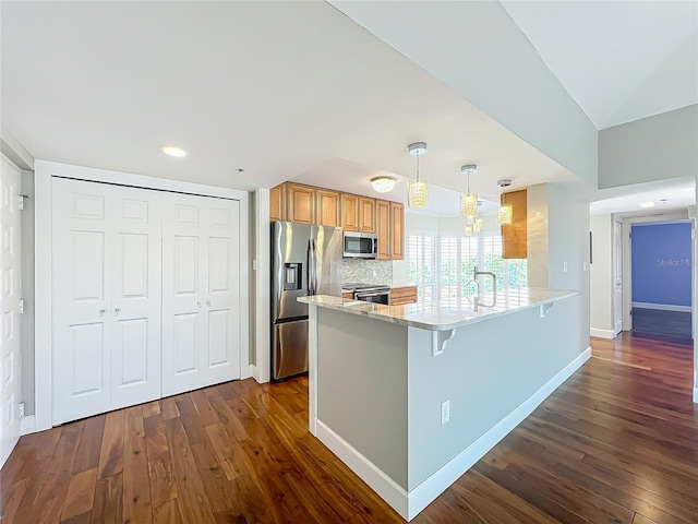 204 Quayside Cir Unit 601, Maitland, FL 32751 - kitchen with appliances with stainless steel finishes, a peninsula, dark wood-style floors, a kitchen breakfast bar, and light stone counters