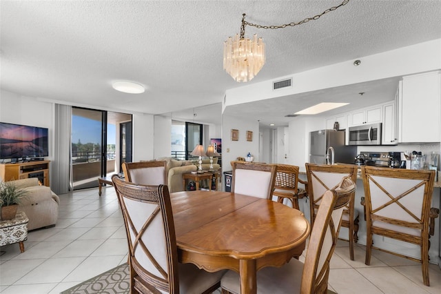 3023 S Atlantic Ave Unit 2050, Daytona Beach, FL 32118 - dining space with light tile patterned floors, a textured ceiling, a chandelier, and a wall of windows