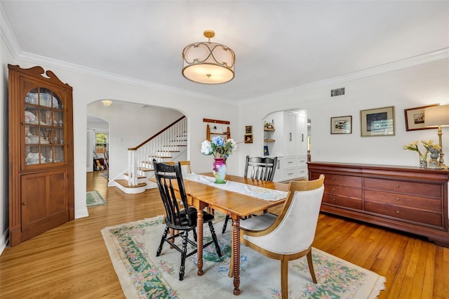 624 Richmond St, Orlando, FL 32806 - dining space featuring arched walkways, stairway, ornamental molding, and light wood-style floors