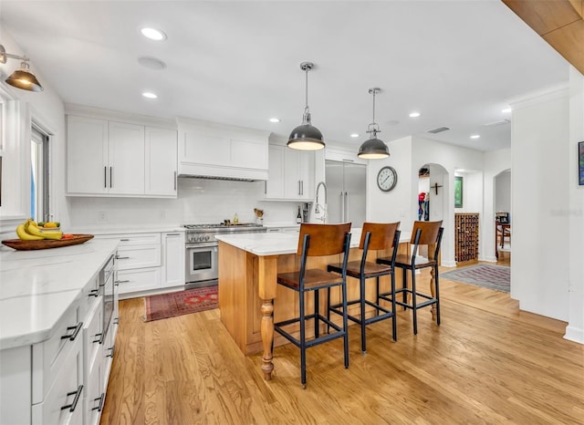 624 Richmond St, Orlando, FL 32806 - kitchen with high end stainless steel range, arched walkways, light wood finished floors, recessed lighting, and decorative backsplash