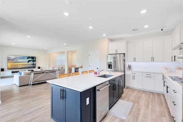 5677 Cedar Chase Dr, Saint Cloud, FL 34771 - kitchen with appliances with stainless steel finishes, white cabinetry, an island with sink, light wood-type flooring, and recessed lighting