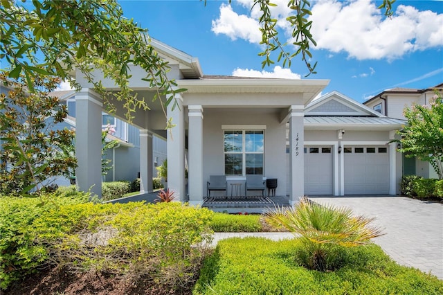 14189 Larkspur Lake Dr, Winter Garden, FL 34787 - view of front of home featuring a porch, an attached garage, a standing seam roof, and stucco siding