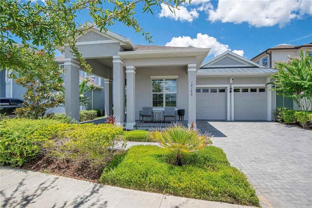 14189 Larkspur Lake Dr, Winter Garden, FL 34787 - view of front of home with a porch, a garage, a standing seam roof, decorative driveway, and stucco siding