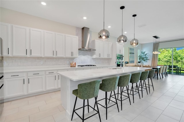 14189 Larkspur Lake Dr, Winter Garden, FL 34787 - kitchen with wall chimney exhaust hood, a spacious island, decorative backsplash, white cabinetry, and recessed lighting