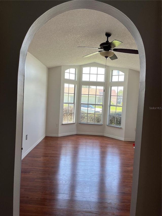 2421 Queenswood Cir, Kissimmee, FL 34743 - empty room featuring arched walkways, ceiling fan, dark wood-style floors, a textured ceiling, and vaulted ceiling