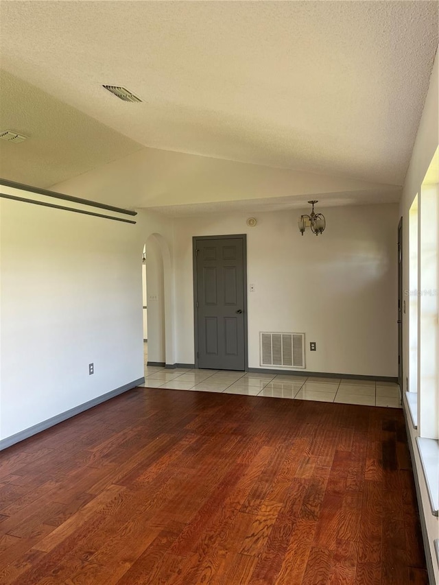 2421 Queenswood Cir, Kissimmee, FL 34743 - empty room with lofted ceiling, light wood-type flooring, arched walkways, and a chandelier