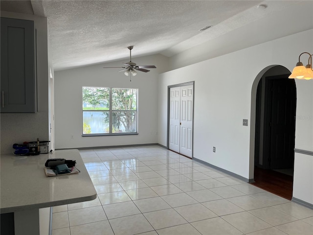 2421 Queenswood Cir, Kissimmee, FL 34743 - spare room featuring arched walkways, lofted ceiling, ceiling fan, light tile patterned flooring, and a textured ceiling