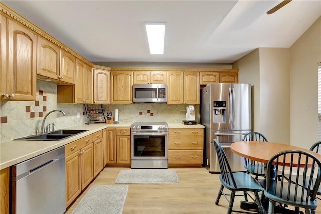 kitchen with appliances with stainless steel finishes, light wood-style floors, backsplash, and light countertops