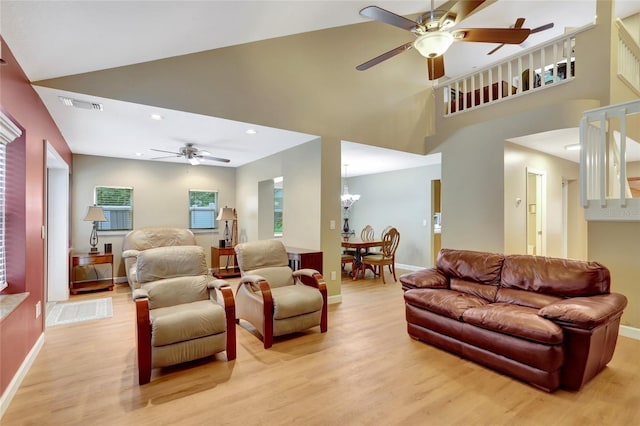 living area featuring ceiling fan, light wood-style floors, a high ceiling, recessed lighting, and a chandelier