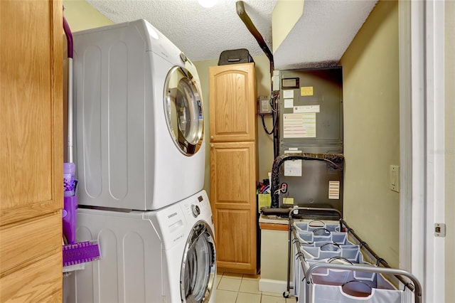 washroom featuring estacked washer and dryer, cabinet space, light tile patterned floors, and a textured ceiling