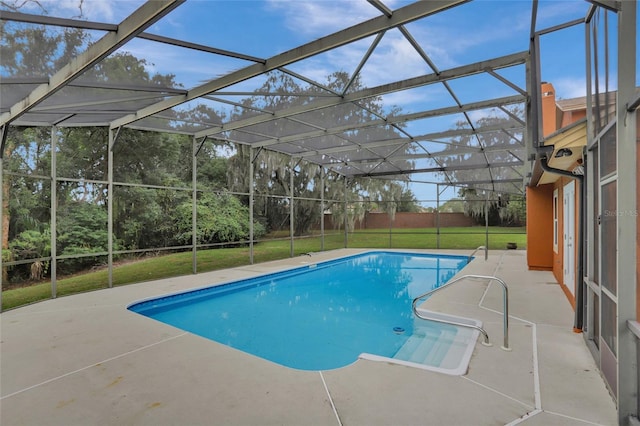outdoor pool featuring a patio area, glass enclosure, and a yard