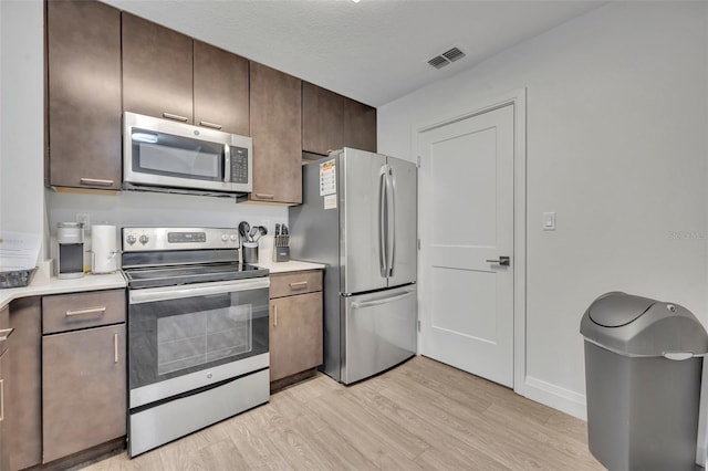 14501 Grove Resort Ave Unit 3239, Winter Garden, FL 34787 - kitchen with appliances with stainless steel finishes, light wood-type flooring, light countertops, and dark brown cabinets
