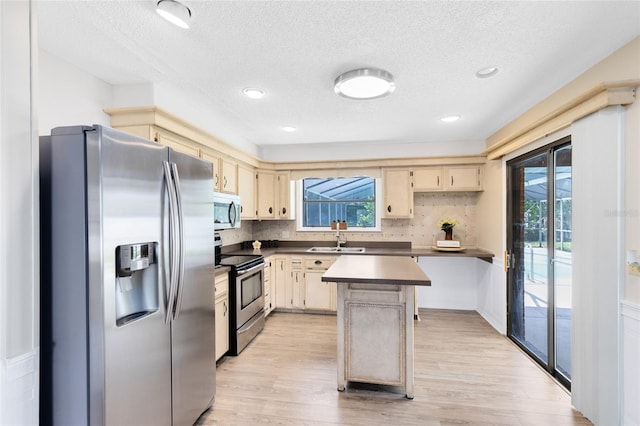 1736 Saxon Blvd, Deltona, FL 32725 - kitchen featuring appliances with stainless steel finishes, cream cabinetry, light wood-style flooring, a textured ceiling, and tasteful backsplash