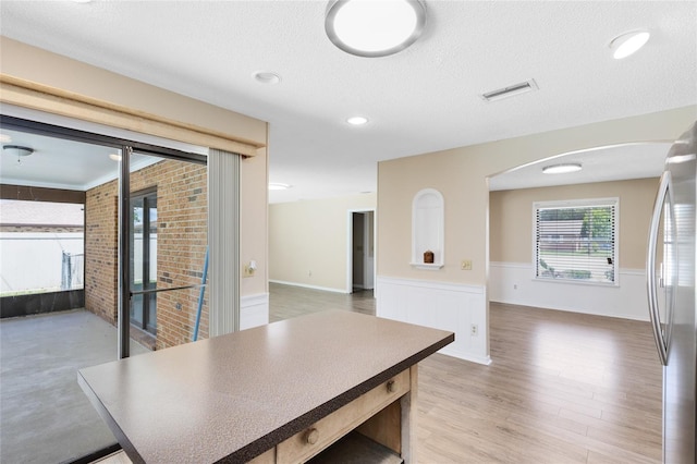 1736 Saxon Blvd, Deltona, FL 32725 - dining room with wainscoting, healthy amount of natural light, arched walkways, light wood-style flooring, and a textured ceiling