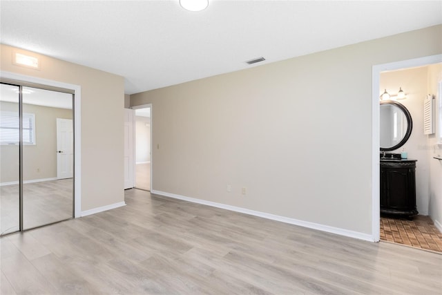 1736 Saxon Blvd, Deltona, FL 32725 - unfurnished bedroom featuring light wood-type flooring, a closet, and connected bathroom