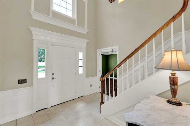 991 Hawthorne Cove Ct, Ocoee, FL 34761 - foyer entrance featuring a decorative wall, a towering ceiling, a wainscoted wall, stairway, and light tile patterned flooring