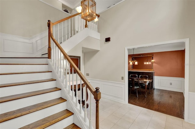 991 Hawthorne Cove Ct, Ocoee, FL 34761 - stairway featuring a decorative wall, wainscoting, a chandelier, tile patterned flooring, and crown molding