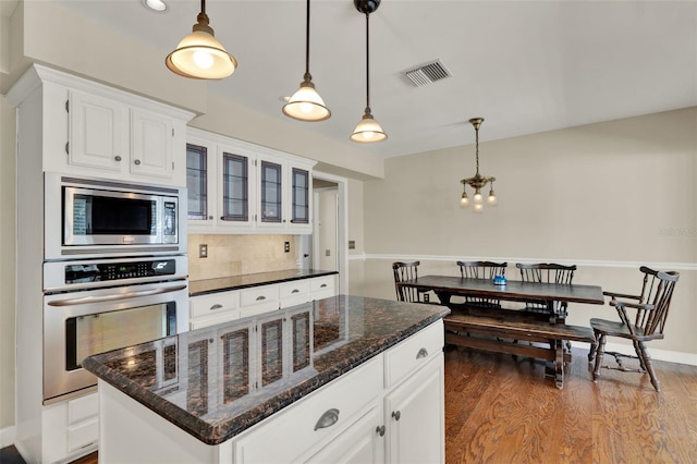 991 Hawthorne Cove Ct, Ocoee, FL 34761 - kitchen featuring appliances with stainless steel finishes, white cabinetry, backsplash, dark wood-type flooring, and hanging light fixtures