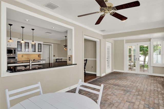 991 Hawthorne Cove Ct, Ocoee, FL 34761 - kitchen with appliances with stainless steel finishes, a ceiling fan, glass insert cabinets, french doors, and tasteful backsplash