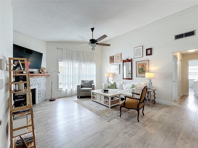 260 Killarney Bay Ct Unit 6-6, Winter Park, FL 32789 - living room featuring a ceiling fan, wooden walls, a textured ceiling, light wood-style floors, and a tiled fireplace