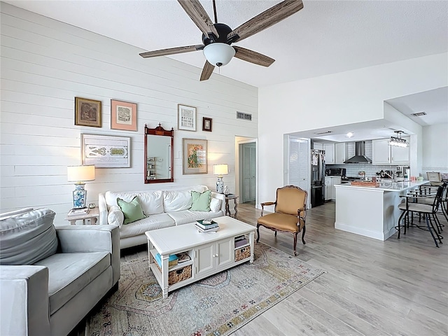 260 Killarney Bay Ct Unit 6-6, Winter Park, FL 32789 - living room with a ceiling fan, light wood finished floors, wood walls, lofted ceiling, and a textured ceiling