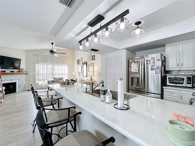 260 Killarney Bay Ct Unit 6-6, Winter Park, FL 32789 - kitchen with stainless steel appliances, a kitchen bar, open floor plan, ceiling fan, and a tiled fireplace