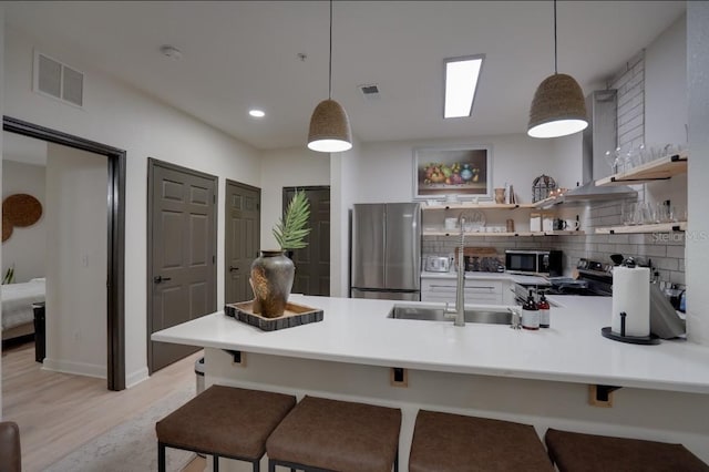 3176 Feltrim Pl Unit 302, Kissimmee, FL 34747 - kitchen with stainless steel appliances, a peninsula, open shelves, light wood-style flooring, and tasteful backsplash