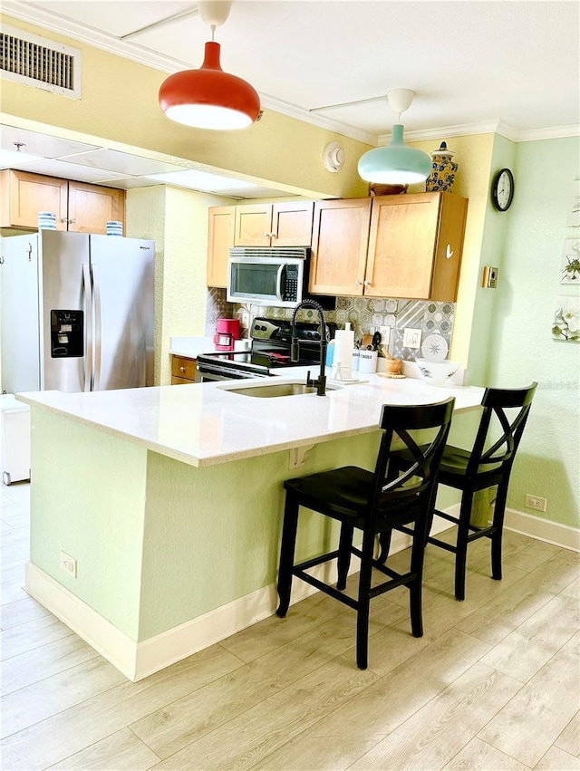 151 E Washington St Unit 508, Orlando, FL 32801 - kitchen featuring appliances with stainless steel finishes, a peninsula, light wood-style floors, tasteful backsplash, and crown molding