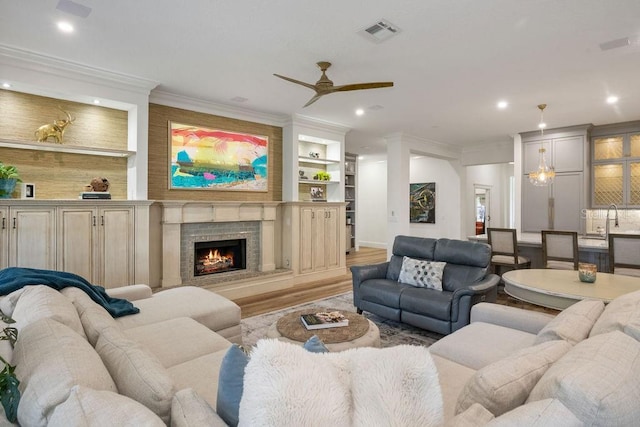 6047 Blakeford Dr, Windermere, FL 34786 - living room featuring a ceiling fan, wood finished floors, crown molding, recessed lighting, and a warm lit fireplace