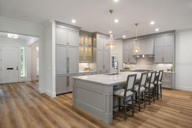 6047 Blakeford Dr, Windermere, FL 34786 - kitchen with gray cabinets, ornamental molding, backsplash, a large island with sink, and light wood finished floors