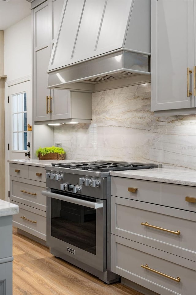 6047 Blakeford Dr, Windermere, FL 34786 - kitchen with stainless steel stove, gray cabinets, premium range hood, and decorative backsplash