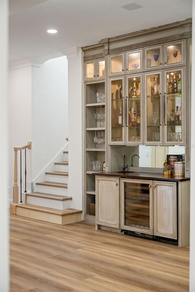 6047 Blakeford Dr, Windermere, FL 34786 - indoor wet bar featuring wine cooler, light wood-style floors, ornamental molding, stairs, and recessed lighting