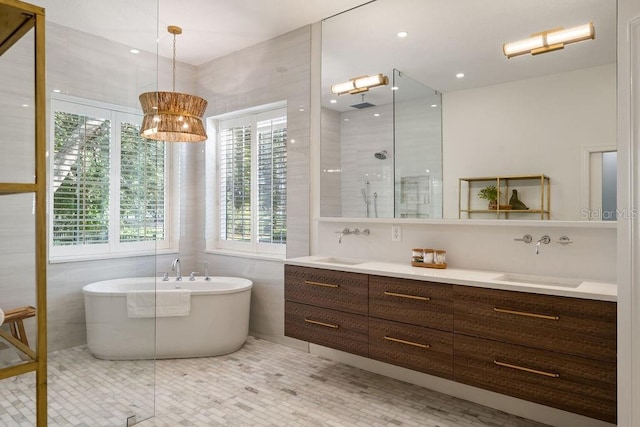 6047 Blakeford Dr, Windermere, FL 34786 - full bath with double vanity, a freestanding tub, a shower with door, tile walls, and tile patterned flooring